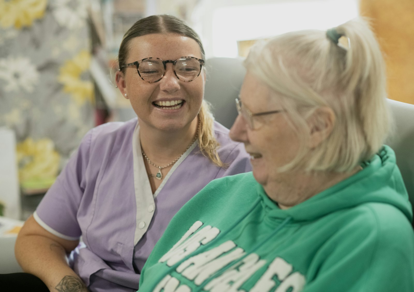 A care worker and an older resident laughing together