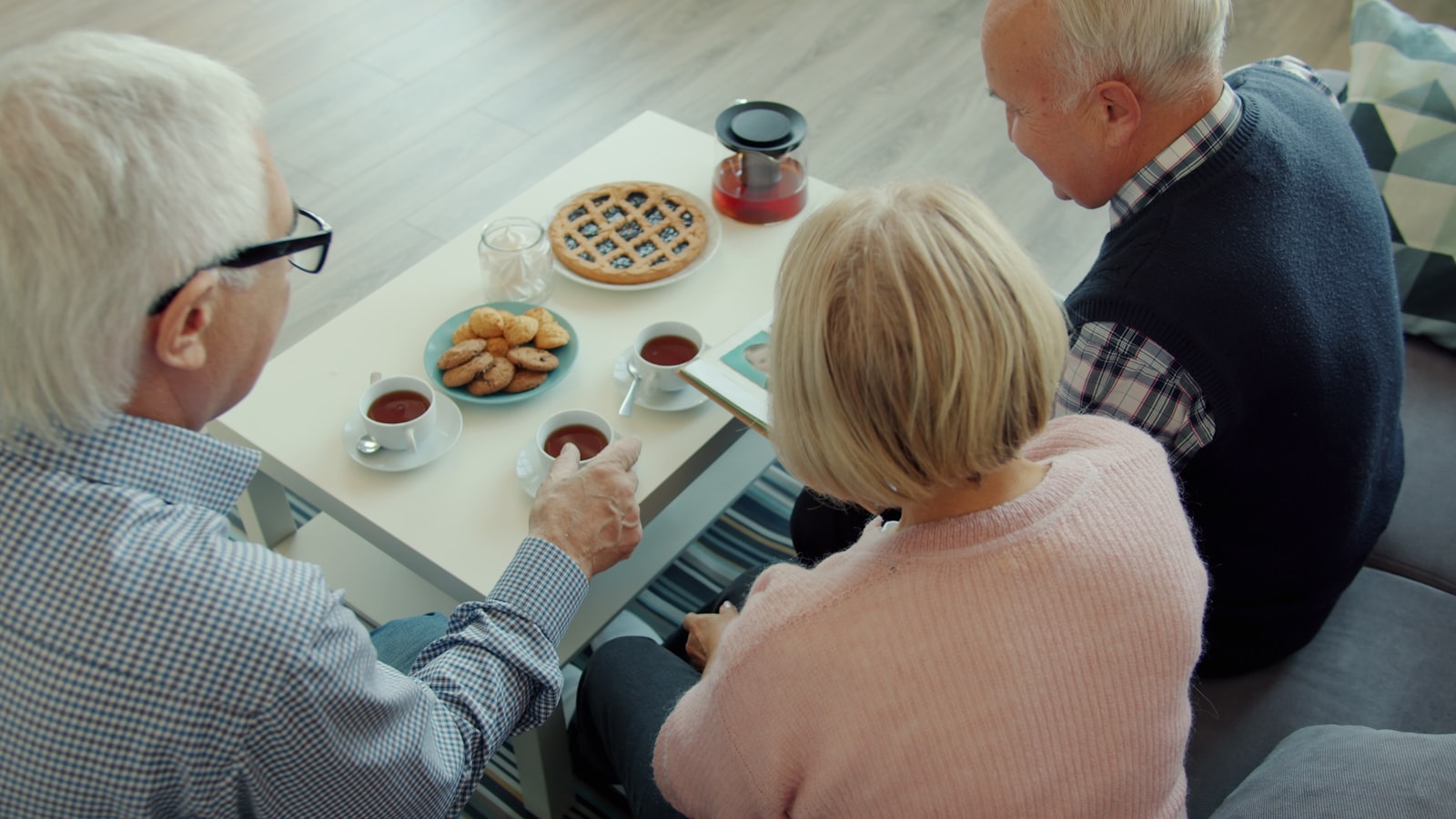 Three older adults sharing tea and pie around a table